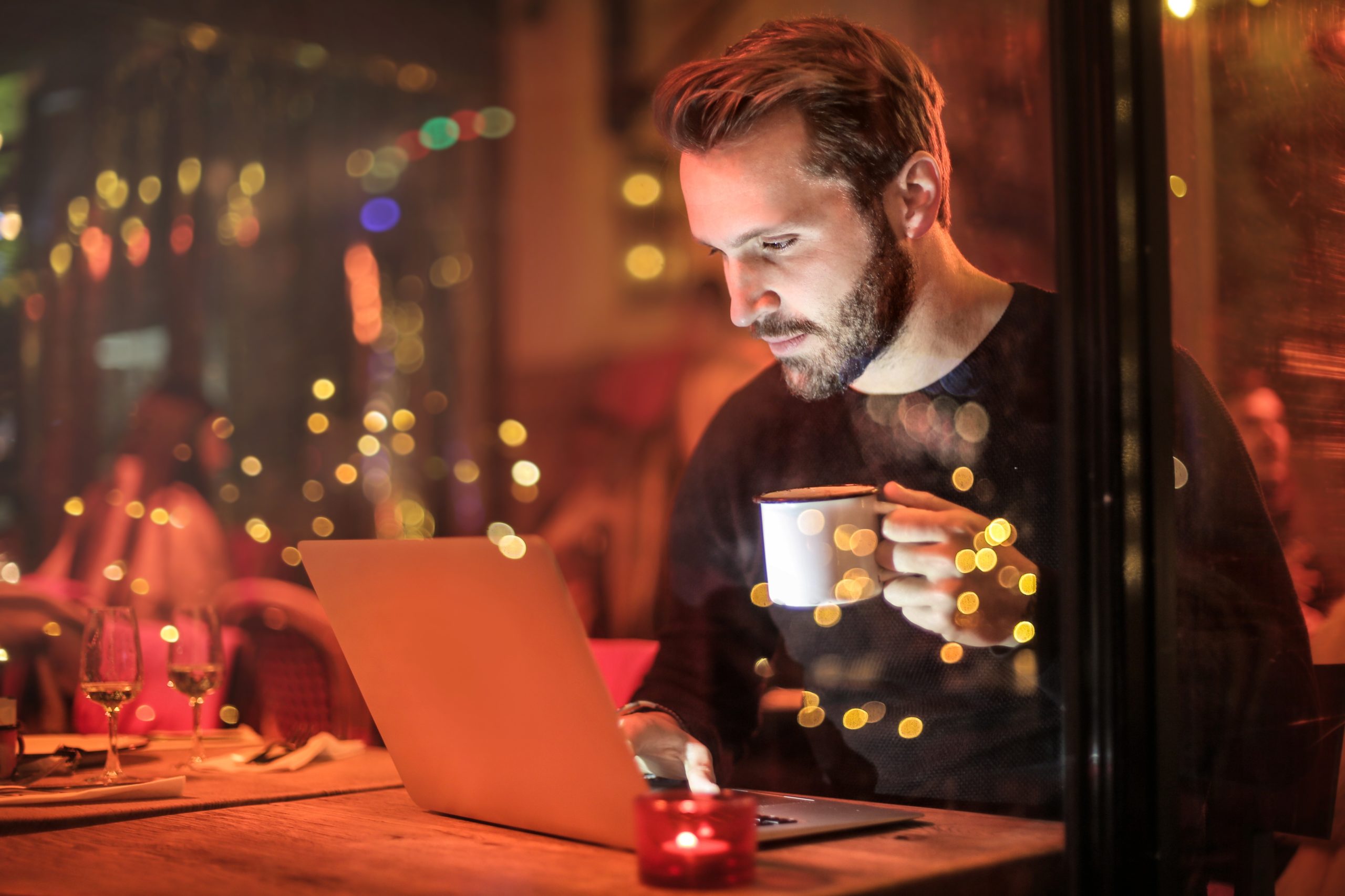 man-holding-mug-in-front-of-laptop